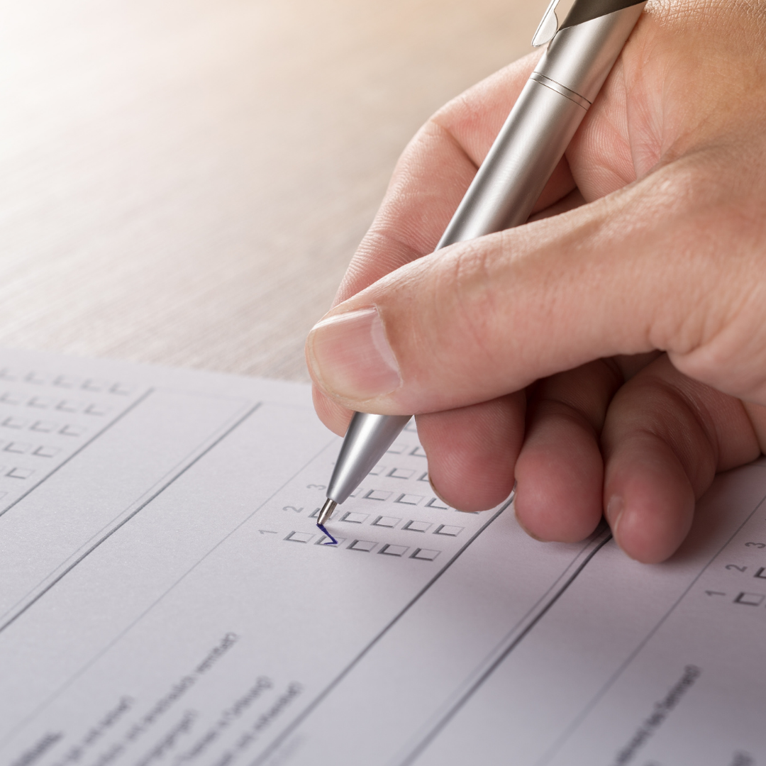 En blankett på ett bord fylls i av en hand som hpller i en kulspetspenna.