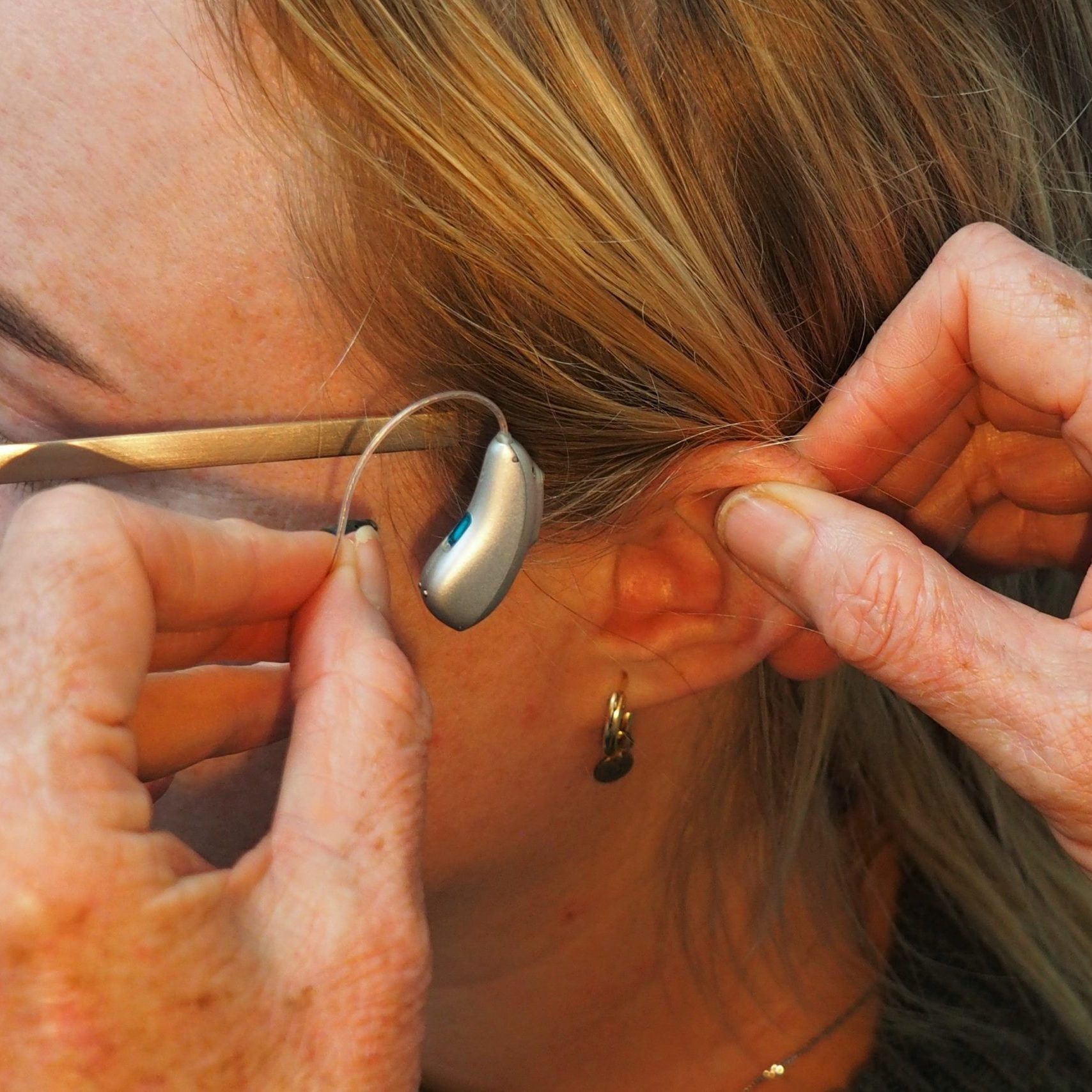 En person sätter på en hörapparat.